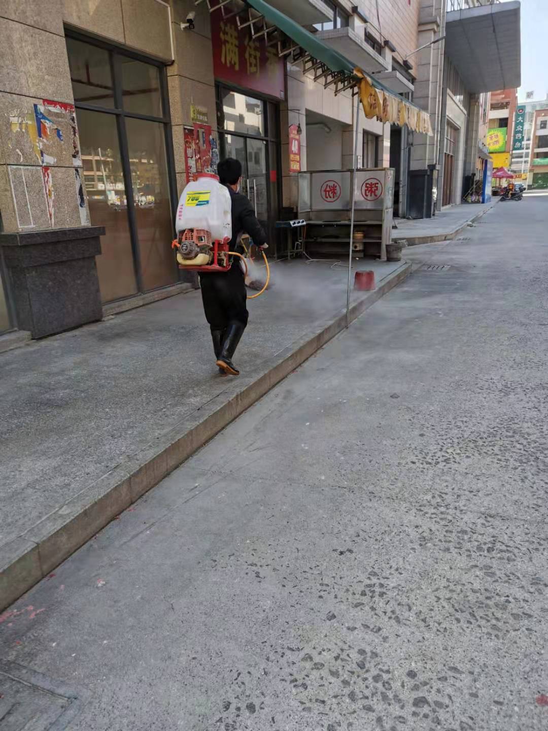 工作人員對店鋪前的街道進行消毒