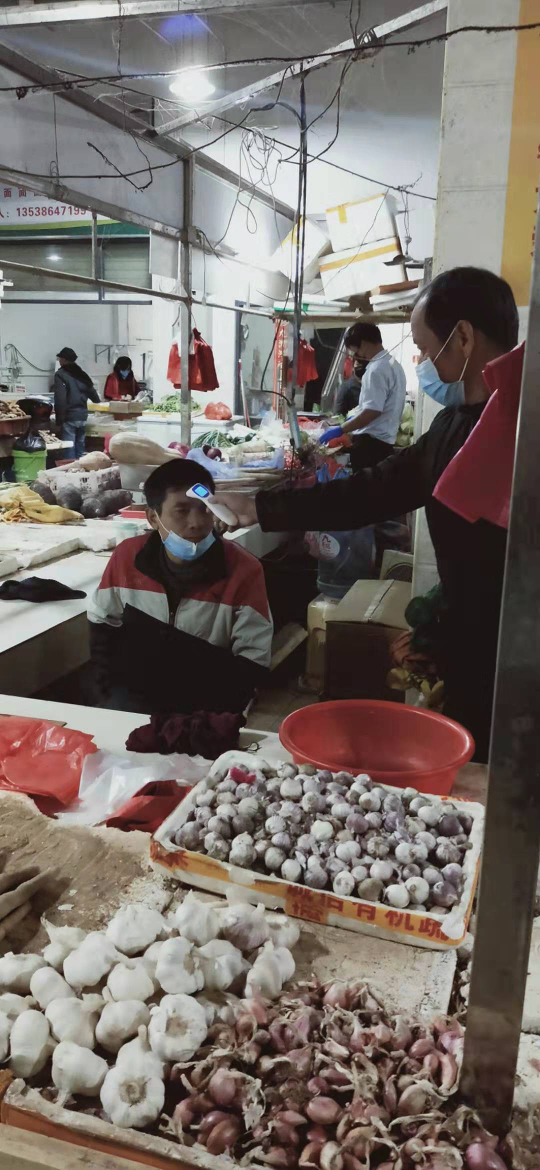工作人員對商戶檢測體溫